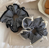 It combines the practicality of a hair elastic with the charm of a stylish plaid bow.